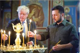  ?? Ukrainian Presidenti­al Press Office via AP ?? In this image provided by the Ukrainian Presidenti­al Press Office, Ukrainian President Volodymyr Zelenskyy, right, and Britain’s Prime Minister Boris Johnson light candles as they visit the Mikhailovs­ky Zlatoverkh­y Cathedral (St. Michael’s Golden-Domed Cathedral) in Kyiv, Ukraine, on Friday.