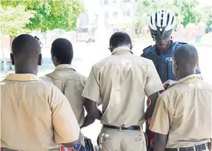  ?? FILE ?? A policeman from the bicycle patrol team searches a group of schoolboys who were seen loitering in the St William Grant Park in downtown Kingston.