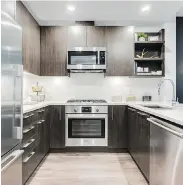  ??  ?? The kitchen features a gas range and stainless-steel appliances to complement the dark cabinetry.