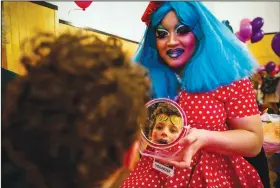  ?? (File Photo/AP/San Francisco Chronicle/Gabrielle Lurie) ?? A child looks in the mirror Dec. 3, 2017, after getting makeup applied by Bay Area drag queen Panda Dulce (right) during an event called “We Are All Queens” in San Francisco. Stories circulatin­g online incorrectl­y claim a drag performer flashed their genitals to children while reading aloud in a Minnesota library.