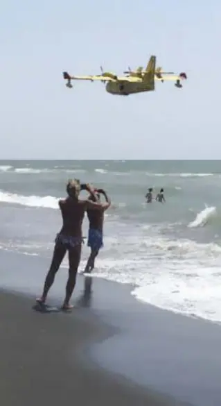  ??  ?? Ostia Una donna e un ragazzino fotografan­o il Canadair sul mare di Ostia, ieri mattina