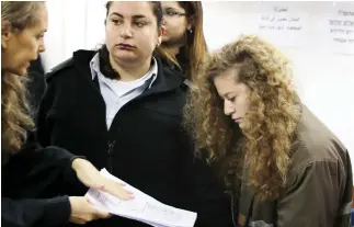  ??  ?? Palestinia­n teen Ahed Tamimi, right, looks at a document handed to her by lawyer Gaby Lasky at the military courtroom at Ofer Prison, near Ramallah, on Tuesday. (Reuters)