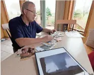  ?? MARK HOFFMAN / MILWAUKEE JOURNAL SENTINEL ?? Wayne Weis, whose Stoughton home was destroyed by a tornado in 2005, looks through photos that were found in Waukesha County after the storm and returned to him. He now lives in a house built on the lot of his former home.