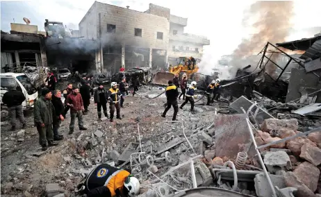  ?? — AFP photo ?? Members of the Syrian Civil Defence, also known as the White Helmets, extinguish a fire at the site of a regime air strike in Syria’s last major opposition bastion of Idlib.