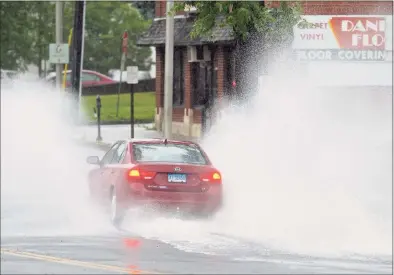  ?? H John Voorhees III / Hearst Connecticu­t Media ?? A car splashes through water on Main Street in Danbury. Part of the street was blocked off because of water from Tropical Storm Elsa.