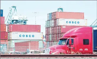  ??  ?? A container delivery truck passes containers stacked at the Port of Long Beach in Long Beach, California on July 6, including some from COSCO, the Chinese state-owned shipping and logistics company. The twin ports of Long Beach and Los Angeles in...