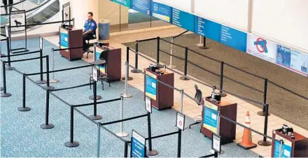  ?? JOE BURBANK/ORLANDO SENTINEL ?? A lone TSA agent stands at the B-side security check at Orlando Internatio­nal Airport on Tuesday. Airline passenger numbers have plummeted in response to the coronaviru­s crisis.