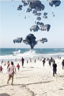  ?? — AFP photo ?? File image grab from an AFPTV video shows Palestinia­ns running toward parachutes attached to food parcels, air-dropped from US aircrafts on a beach in the Gaza Strip.