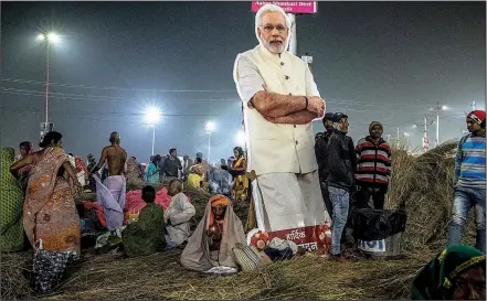  ?? The New York Times/BRYAN DENTON ?? A cardboard cutout of Prime Minister Narendra Modi of India stands among attendees of the Kumbh Mela religious festival in India. The festival has been even bigger this year, infused with the governing party’s cash and advertisem­ents during high campaign season.