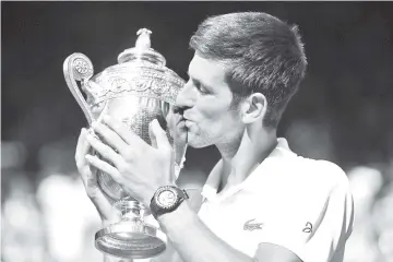  ?? - AFP photo ?? Serbia’s Novak Djokovic kisses the winners trophy after beating South Africa’s Kevin Anderson 6-2, 6-2, 7-6 in their men’s singles final match on the thirteenth day of the 2018 Wimbledon Championsh­ips at The All England Lawn Tennis Club in Wimbledon,...