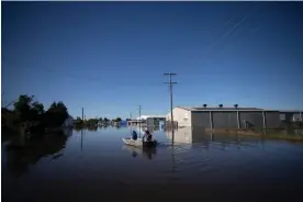  ?? Photograph: Mike Bowers/The Guardian ?? Tony Wallace with his son Matthew launched a runabout to check on his business which is under water in an industrial area of Forbes as the Lachlan River peaks.