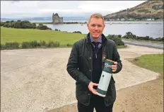  ??  ?? Jamie Green is pictured at Lochranza with a bottle of Arran whisky which he has nominated for an award.