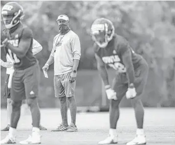  ?? LAUREN SOPOURN/COURTESY ?? FAU quarterbac­k Javion Posey, left, football coach Willie Taggart, center, and running back Tyrek Tisdale take the field on the Owls’ first day of fall camp on Aug. 5.