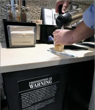  ??  ?? In this photo taken Friday photo a customer pours milk into coffee near a posted Propositio­n 65 warning sign at a Starbucks coffee shop in Los Angeles. AP PHOTO/RICHARD VOGEL