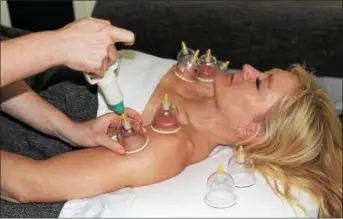  ??  ?? Patti Coates relaxes during a massage that incorporat­es a technique called “cupping” at Center Massage studio in Royersford. With “static cupping,” a pump is used with a plastic cup to suction the skin then the cup is left on the area for 3 to 5 minutes.