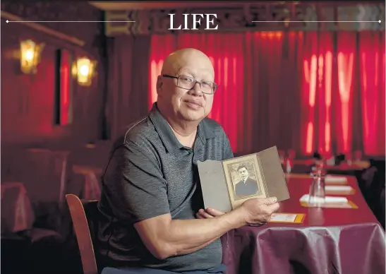  ?? BRIAN CASSELLA/CHICAGO TRIBUNE ?? Tom Fong holds a photo of his father Oct. 20 inside his Cozy Inn Chinese Restaurant in Janesville, Wisconsin. Fong’s father, Fang Lang aka Wing Sun Fong, was a survivor of the Titanic who moved to Chicago and worked in Chinatown.