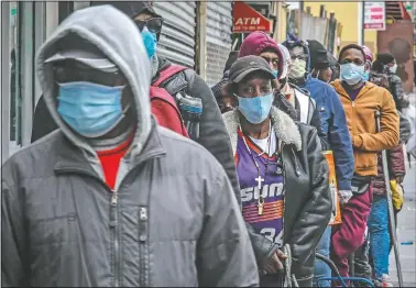  ??  ?? People wait April 18 for a distributi­on of masks and food in the Harlem neighborho­od of New York.