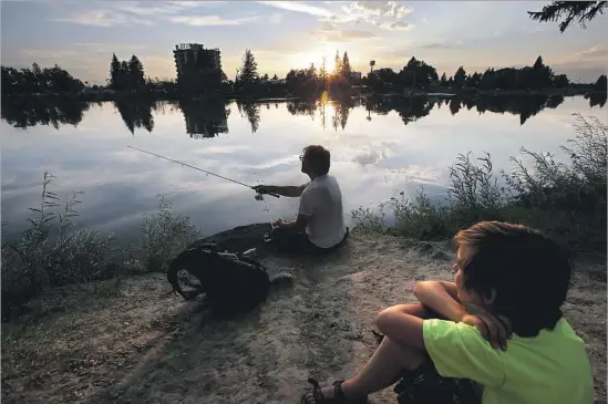  ?? Photograph­s by Luis Sinco Los Angeles Times ?? JAMES HATHAWAY and his son, Alex, fish on the banks of the Snake River in Idaho Falls. The town’s population could swell 10 times with Monday’s solar eclipse.