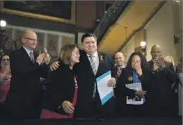  ?? Brian Cassella Chicago Tribune ?? GOV. J.B. PRITZKER hugs gun control advocate Maria Pike, who lost her son to gun violence, after he signed legislatio­n to ban semiautoma­tic weapons Tuesday.