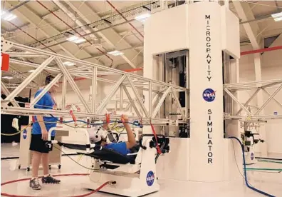  ?? CHABELI HERRERA/STAFF ?? In the microgravi­ty simulator, guests sit in zero-gravity chairs and pull themselves along under a metal crane-like structure, opening boxes, moving switches and turning knobs on a “mission” to repair a space station truss.