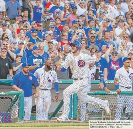  ??  ?? Cubs star Kris Bryant dashes home with the tiebreakin­g run on Anthony Rizzo’s double with two outs in the eighth inning Saturday at Wrigley Field.
| AP