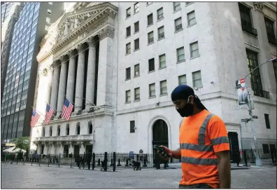  ?? (AP/Mark Lennihan) ?? A man walks past the New York Stock Exchange on Tuesday in New York. Companies that would benefit most from a reopening economy again led the market in trading on Wall Street, as investors look for a rebound in activity.