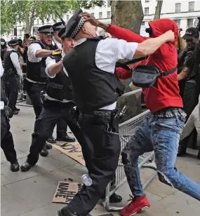  ??  ?? are restrained by police, who were pelted with plastic bottles