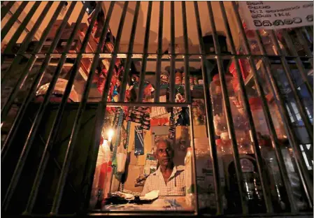  ??  ?? In the dark: A vendor waiting at the cashier table at his shop during the daily power cut in Colombo. — Reuters