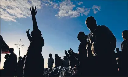  ?? Photo: PETER
MEECHAM ?? Members of the Kingdom Rise Church pray as the sun rises over the cross on Mt Roskill.