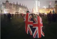  ?? KIRSTY WIGGLESWOR­TH - ASSOCIATED PRESS ?? People draped in UK flags walk across Parliament Square during a rainfall in London on Friday. Britain officially leaves the European Union on Friday after a debilitati­ng political period that has bitterly divided the nation since the 2016 Brexit referendum.