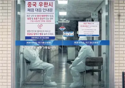  ?? AFP ?? Medical workers wearing protective gear sit in an entrance of a hospital in Daegu on Sunday as they wait for ambulances carrying patients infected with Covid-19.