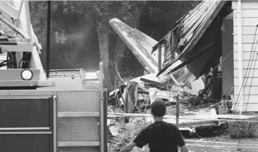  ?? FRED BECKHAM/ THE ASSOCIATED PRESS ?? A firefighte­r surveys the scene of Friday’s crash in East Haven, Conn. Four to six people died.