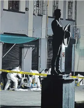  ?? STRINGER THE ASSOCIATED PRESS ?? Workers cover the bodies of victims at the Garibaldi Plaza, a popular tourist spot in Mexico City, after a shooting last Friday killed four people and wounded nine others.