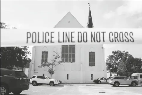  ?? STEPHEN B. MORTON/AP ?? In this June 19, 2015, file photo, police tape surrounds the parking lot behind the AME Emanuel Church as FBI forensic experts work the crime scene, in Charleston, S.C. Families of nine victims killed in a racist attack at the church have reached a settlement with the Justice Department over a faulty background check that allowed Dylann Roof to purchase the gun he used in the 2015 massacre.