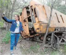  ?? AFP/EFE ?? Tienda de recuerdos en Chernóbil . A la derecha, una visitante se toma un selfi con un autobús abandonado