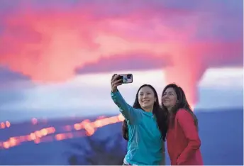  ?? GREGORY BULL AP ?? Ingrid Yang, left, and Kelly Bruno, both of San Diego, take a photo in front of lava erupting from Hawaii’s Mauna Loa volcano near Hilo on Wednesday.