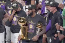  ?? AP file photo ?? LeBron James holds the NBA championsh­ip trophy and the NBA Finals MVP trophy after leading the Lakers to the NBA title on Oct. 11.
