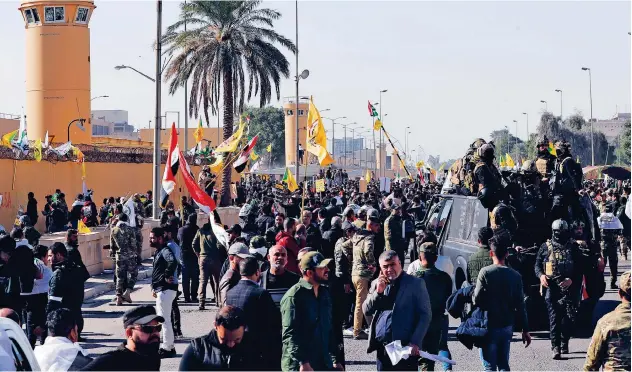  ?? Reuters ?? ↑ Protesters and militia fighters protest outside the main gate of the US Embassy in Baghdad on Tuesday.