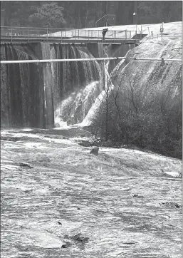  ?? Courtesy photo
/ Dore Bietz ?? A person peers over the edge oftwain Harte Dam onthursday while investigat­ing cracks in the granite slab next to it that resulted in concerns about a potential dam failure and evacuation advisories downstream.