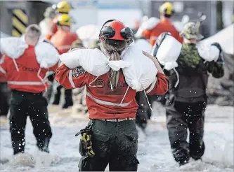  ?? JUSTIN TANG THE CANADIAN PRESS ?? An Ontario Ministry of Natural Resources Fire Ranger carries sandbags to fortify a wall keeping floodwater­s at bay along Alexander Street in Pembroke, Ont., in May.