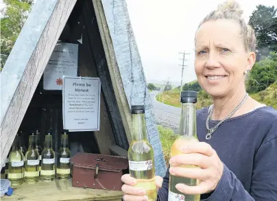  ?? PHOTO: JOHN COSGROVE ?? Stumped . . . Jo Heslop, of Manuka Gorge, restocks her quirky roadside stall with elderflowe­r cordial after 11 bottles, the shelf and the cash box were taken at the weekend.