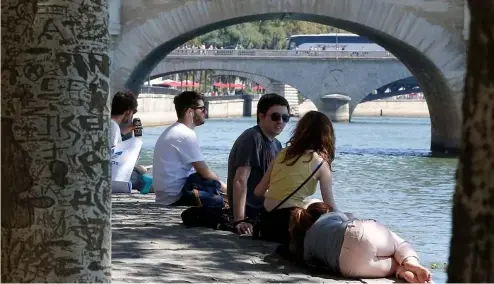  ?? ?? People rest by the bank of the River Seine during a heatwave in summer 2018.