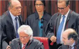  ??  ?? Fallo dividido. Gilmar Mendes, de pie a la izquierda, fue el encargado de desempatar en el Tribunal Superior Electoral y falló a favor de Temer.