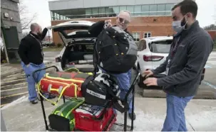  ?? Pam Panchak/Post-Gazette ?? UPMC created a paramedic response team to answer health plan member calls for urgent care that could be provided in the home instead of a hospital. Here, paramedic Dave Buzard loads equipment onto a cart to return to the office while Douglas Crocitto gets ready to steady the cart outside their North Side office.