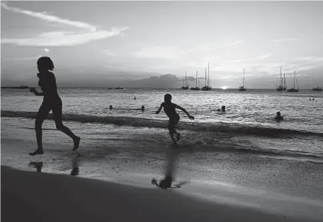  ?? Jewel Samad, AFP/ Getty Images ?? Tourists play on a beach in Bridgetown, Barbados, as the sun sets.