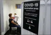  ?? MARCIO JOSE SANCHEZ — THE ASSOCIATED PRESS FILE ?? A patient receives a shot of the Moderna COVID-19 vaccine next to a guidelines sign at a CVS Pharmacy branch in Los Angeles.