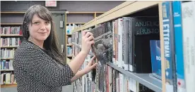  ?? DAVE JOHNSON THE WELLAND TRIBUNE ?? Librarian Rachel Tkachuk places a biography back on the newly-installed accessible shelving at Port Colborne Public Library Saturday during an open house.