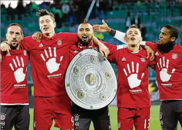  ??  ?? Zum fünften Mal in Serie Erster: Münchens Franck Ribéry, Robert Lewandowsk­i, Arturo Vidal, Rafinha und Douglas Costa (v. l.) feiern mit einer Kopie der Meistersch­ale. Foto: Peter Steffen/dpa