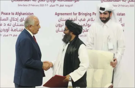  ?? HUSSEIN SAYED — THE ASSOCIATED PRESS ?? U.S. peace envoy Zalmay Khalilzad, left, and Mullah Abdul Ghani Baradar, the Taliban group’s top political leader, shack hands Saturday after signing a peace agreement between Taliban and U.S. officials in Doha, Qatar.