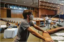  ??  ?? Audiovisua­l technician Nathan Malek helps the synagogue prepare for its cable-TV services, a way to reach more people.